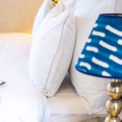 Oreillers blancs avec une lampe bleu motif design sur une table de chevet.