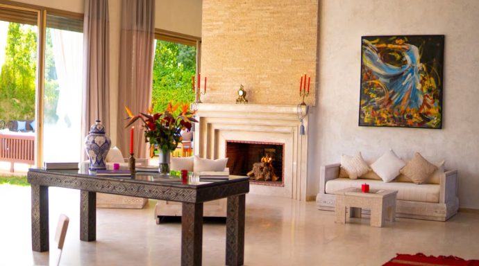 Intérieur moderne avec un salon lumineux, cheminée, table décorée et tableau coloré.